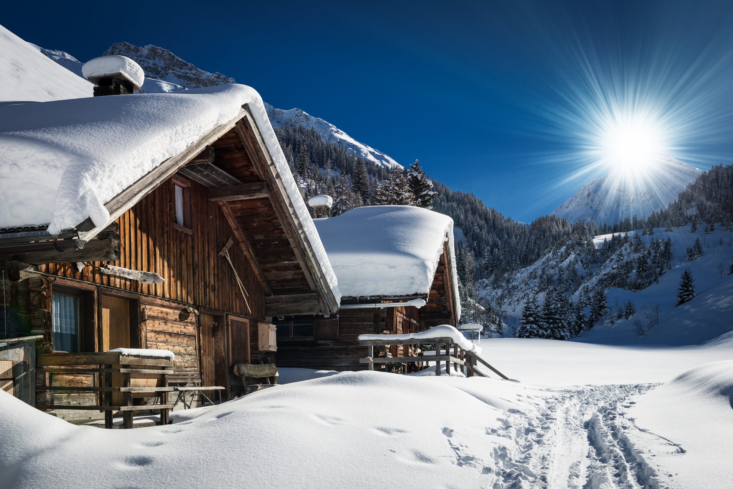 A cozy snow-covered cabin under a bright sun, creating a serene and peaceful winter scene.